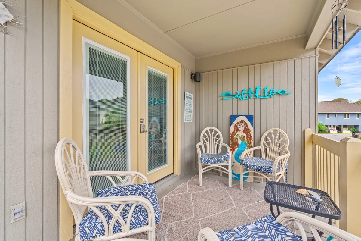 The photo displays an exterior cottage setting with cozy outdoor seating, a decorative sign, and artwork, all bathed in the warm glow of a sunset. The scene invites moments of relaxation and conversation, whether in solitude or with loved ones.