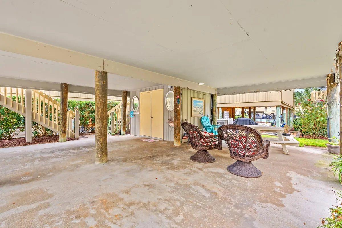 This inviting interior-outdoor space features wicker chairs, a picnic table, and decorative wall art, all set in a bright, open area that blurs the line between inside and outside. It hints at group meals, game nights, and shared experiences in a relaxed, communal setting.
